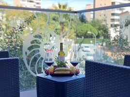 Een balkon tafel met twee wijnglazen, een fles wijn en een fruitschaal.