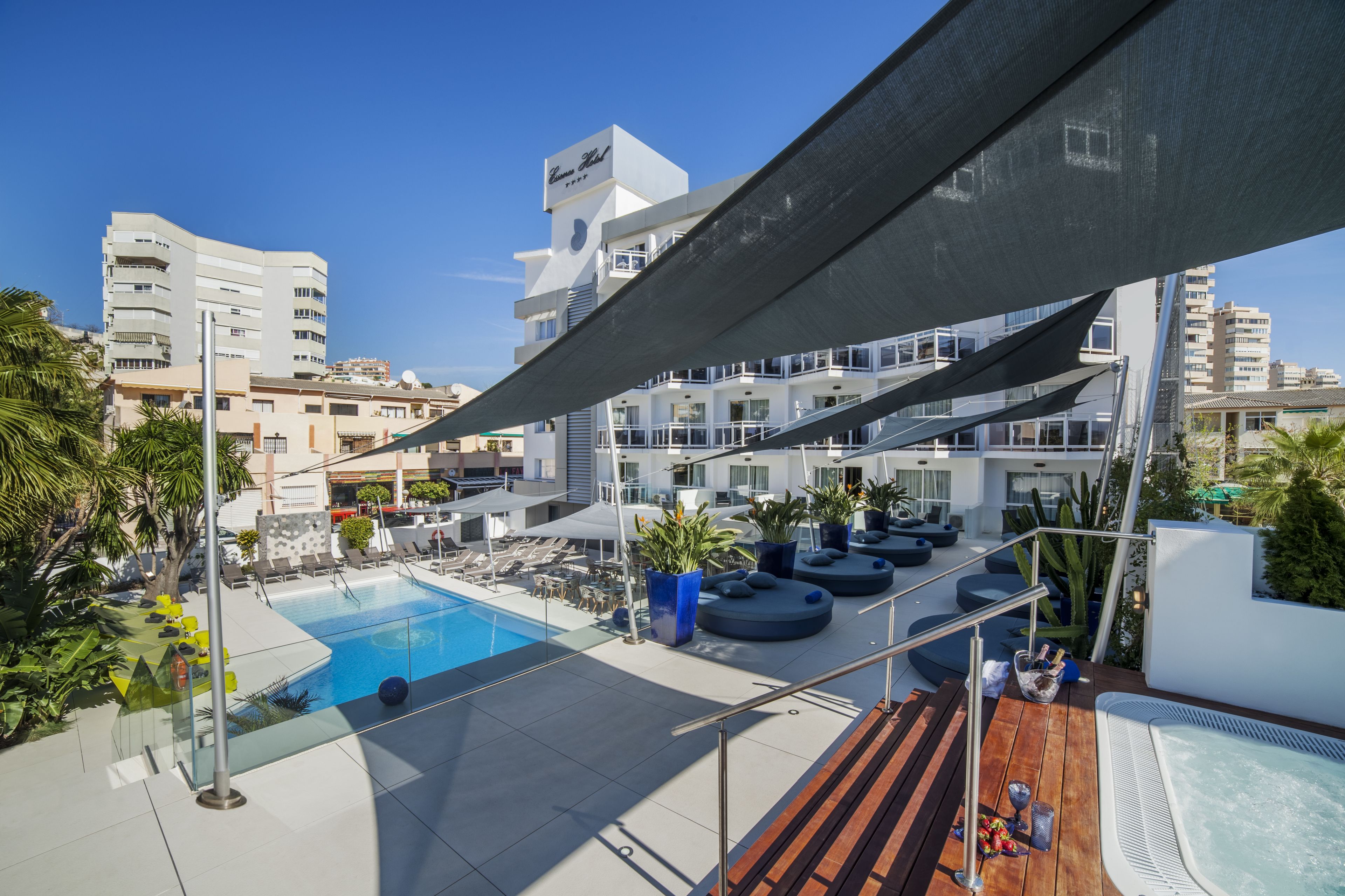 Un espace piscine aménagé sur le toit, avec des chaises longues, un jacuzzi et une vue sur les bâtiments environnants.