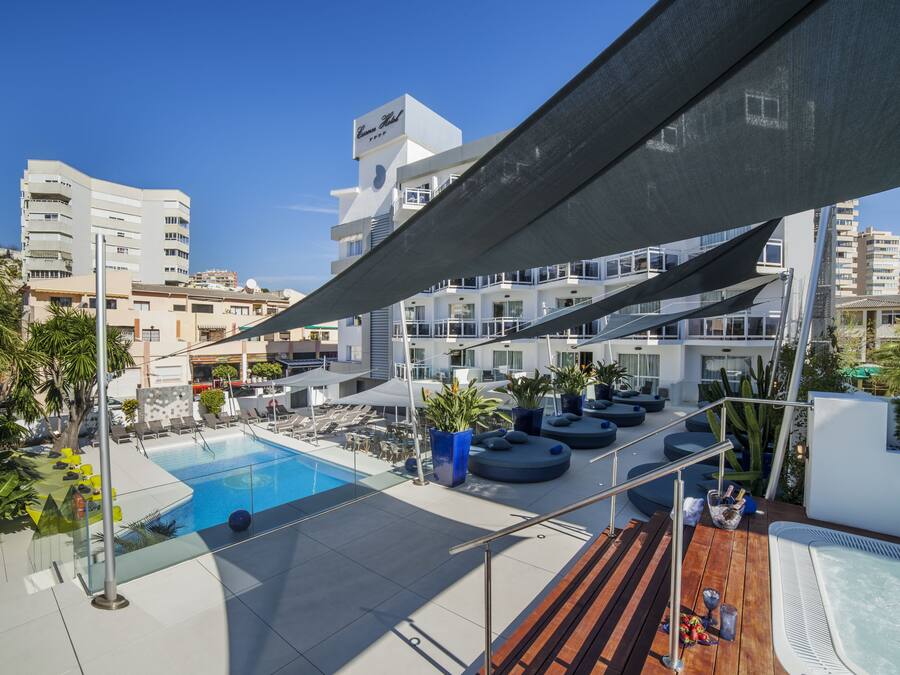 Un espace piscine aménagé sur le toit, avec des chaises longues, un jacuzzi et une vue sur les bâtiments environnants.