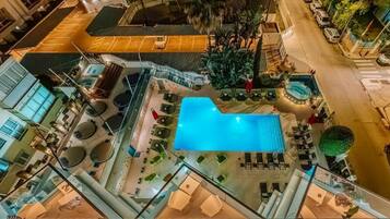 Un espace piscine aménagé sur le toit, avec des chaises longues et une piscine.