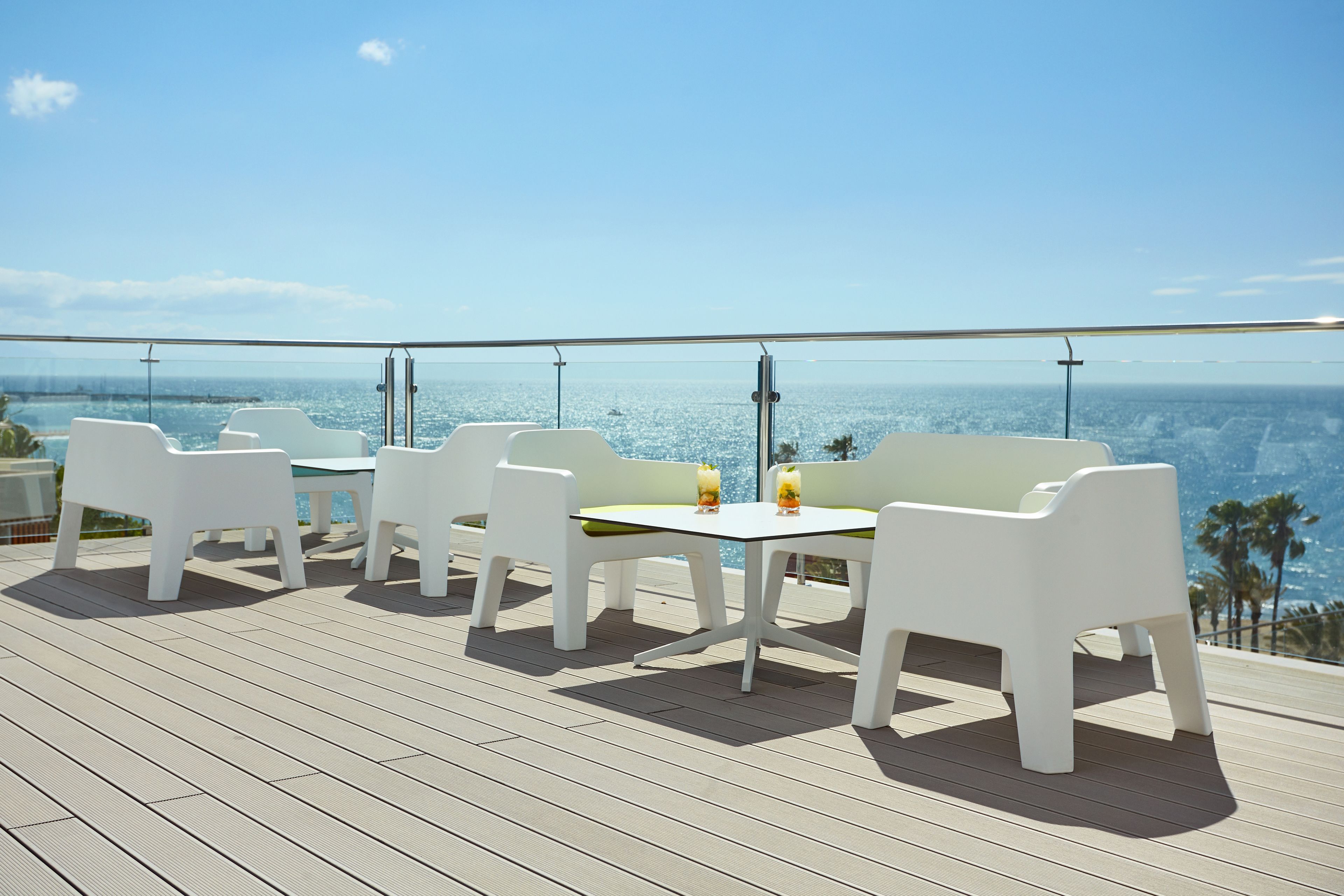 Une terrasse dotée de meubles blancs et d’une table, offrant une vue sur une étendue d’eau.
