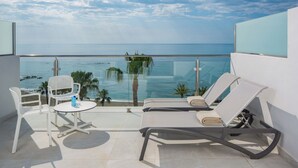 A balcony with a glass railing, white lounge chairs, a small table, and a view of the ocean. - Hotel Las Arenas, Affiliated by Meliá (Benalmádena)