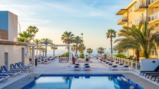 A pool area with lounge chairs and palm trees, overlooking a body of water. - Hotel Las Arenas, Affiliated by Meliá (Benalmádena)