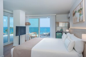 Habitación de hotel con una cama grande, televisión, escritorio y vista al océano.