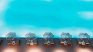Een rij ligbedden met parasols op een dak terras.
