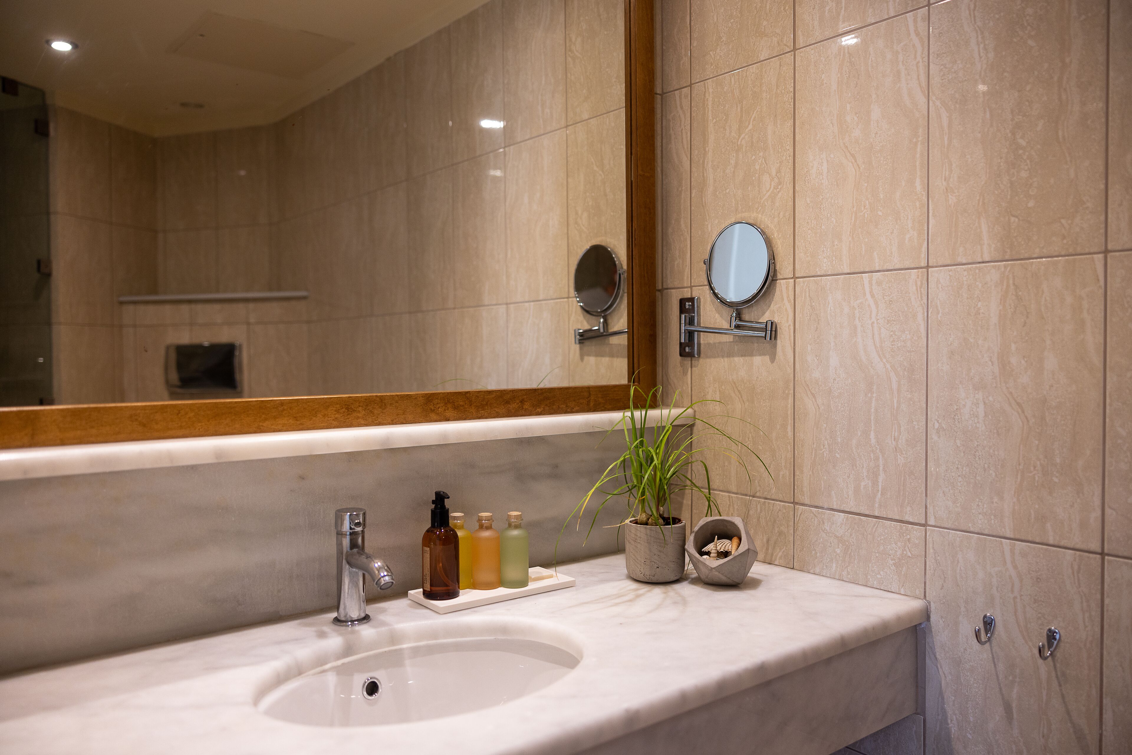 A bathroom with a large mirror, a sink, and toiletries.