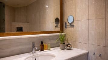 A bathroom with a large mirror, a sink, and toiletries.