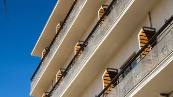 A multi-story building with balconies, each with a metal railing and a small window.