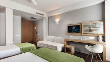 Una habitación de hotel moderna con una cama sofa, un escritorio con una silla, un ventilador de techo y obras de arte en la pared.