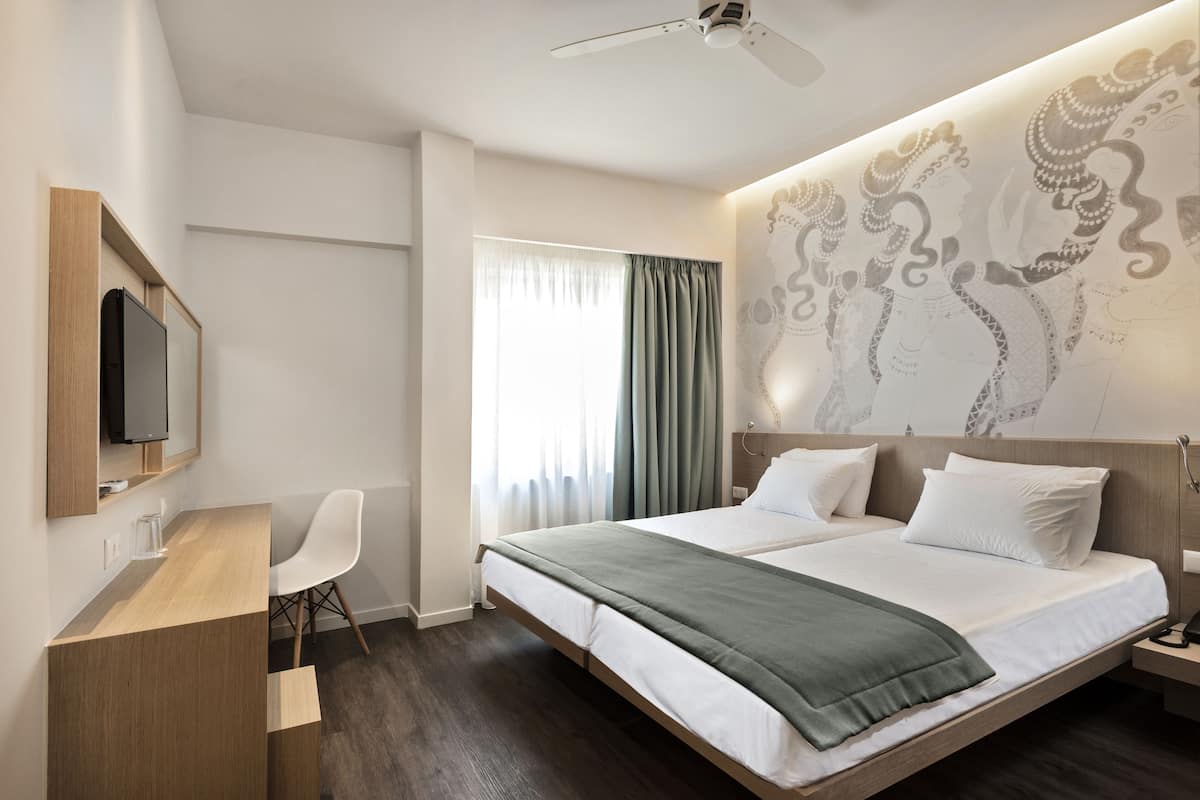 Una habitación de hotel moderna con una cama grande, un escritorio con una silla, un televisor de pantalla plana y un ventilador de techo.