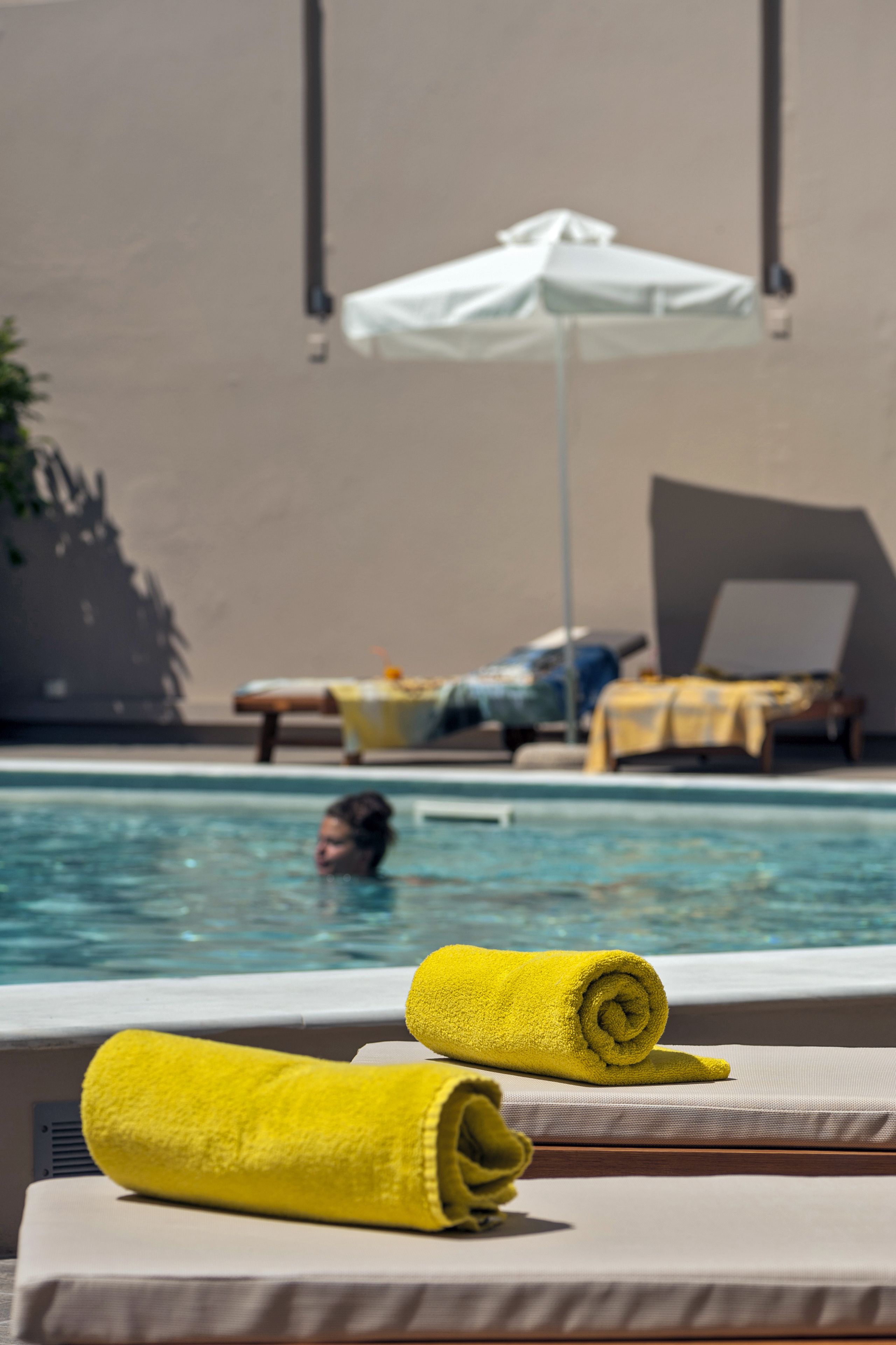 Un espace aménagé au bord de la piscine, avec des chaises longues et un parasol blanc.