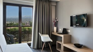 Habitación de hotel moderna con balcón, televisión de pantalla plana, escritorio y zona de estar confortable.