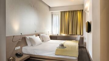 Una habitación de hotel moderna con cama, mesita de noche y escritorio con silla.