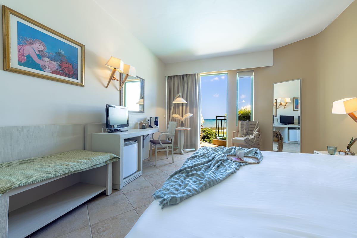 Ein Hotelzimmer mit Bett, Schreibtisch, Stuhl und einem Balkon mit Blick.