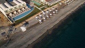 An aerial view of a coastal hotel with a large pool, beachside lounge area, and multiple buildings with balconies. - Giannoulis – Grand Bay Beach Resort - Adults Only (Platanias)