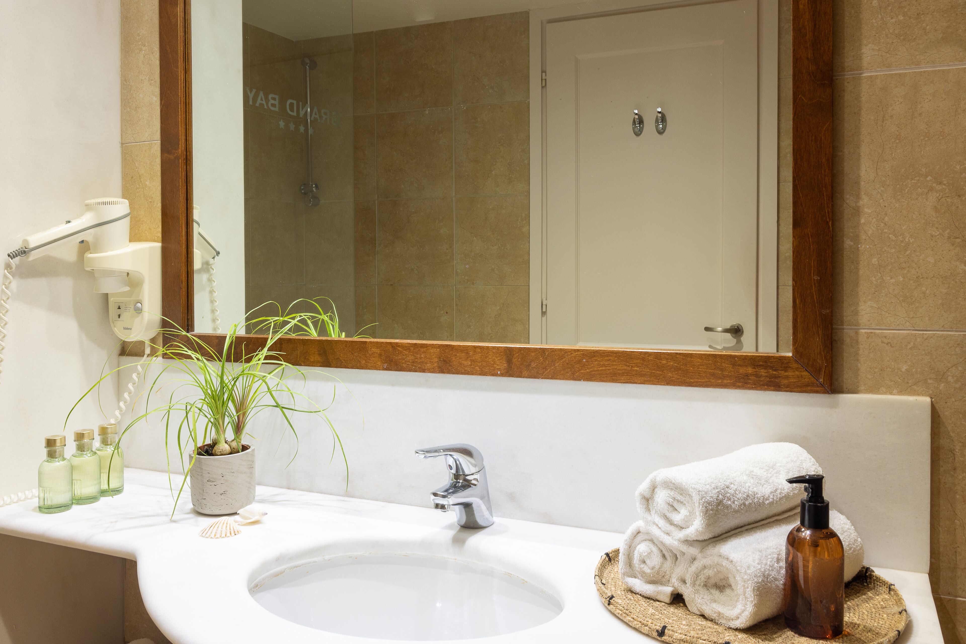 A bathroom with a white sink, a mirror, a towel rack, and toiletries.