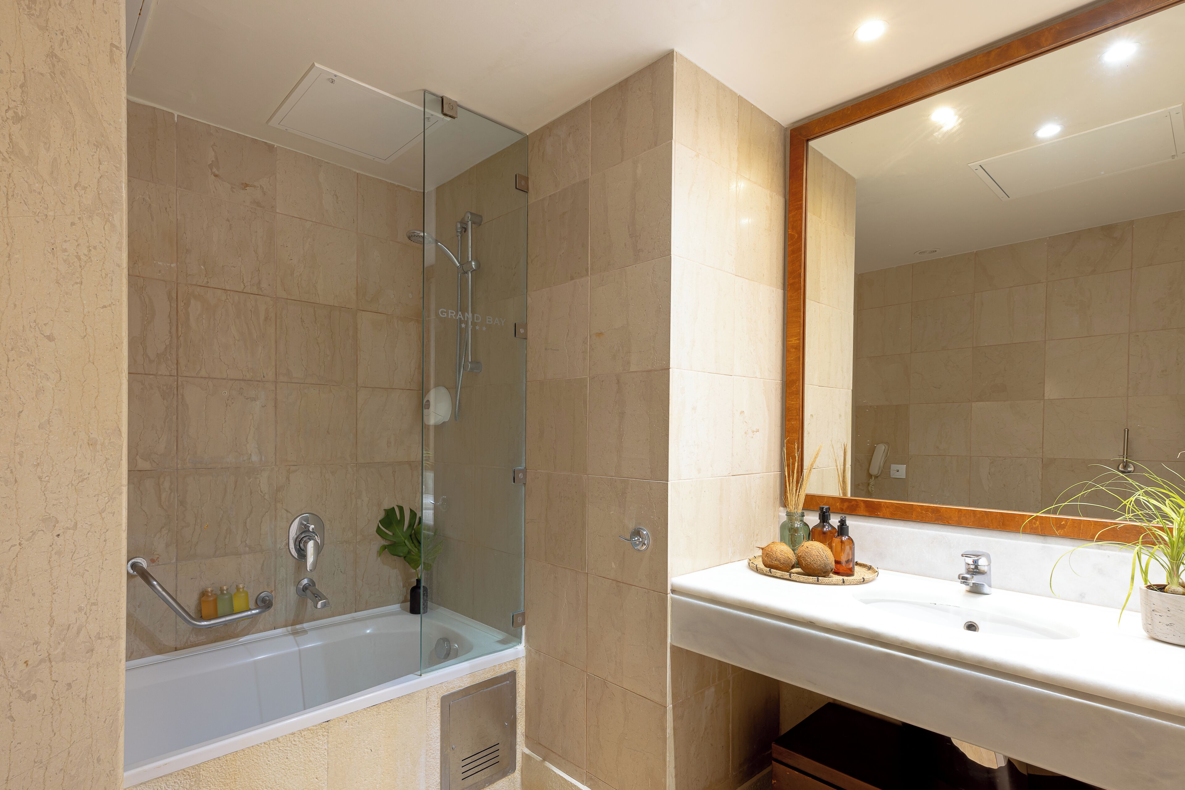 Un baño con bañera, ducha y lavamanos, que incluye un espejo y artículos de aseo.