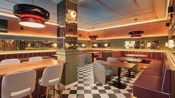 A modern restaurant interior with checkered flooring, booths, and bar seating.
