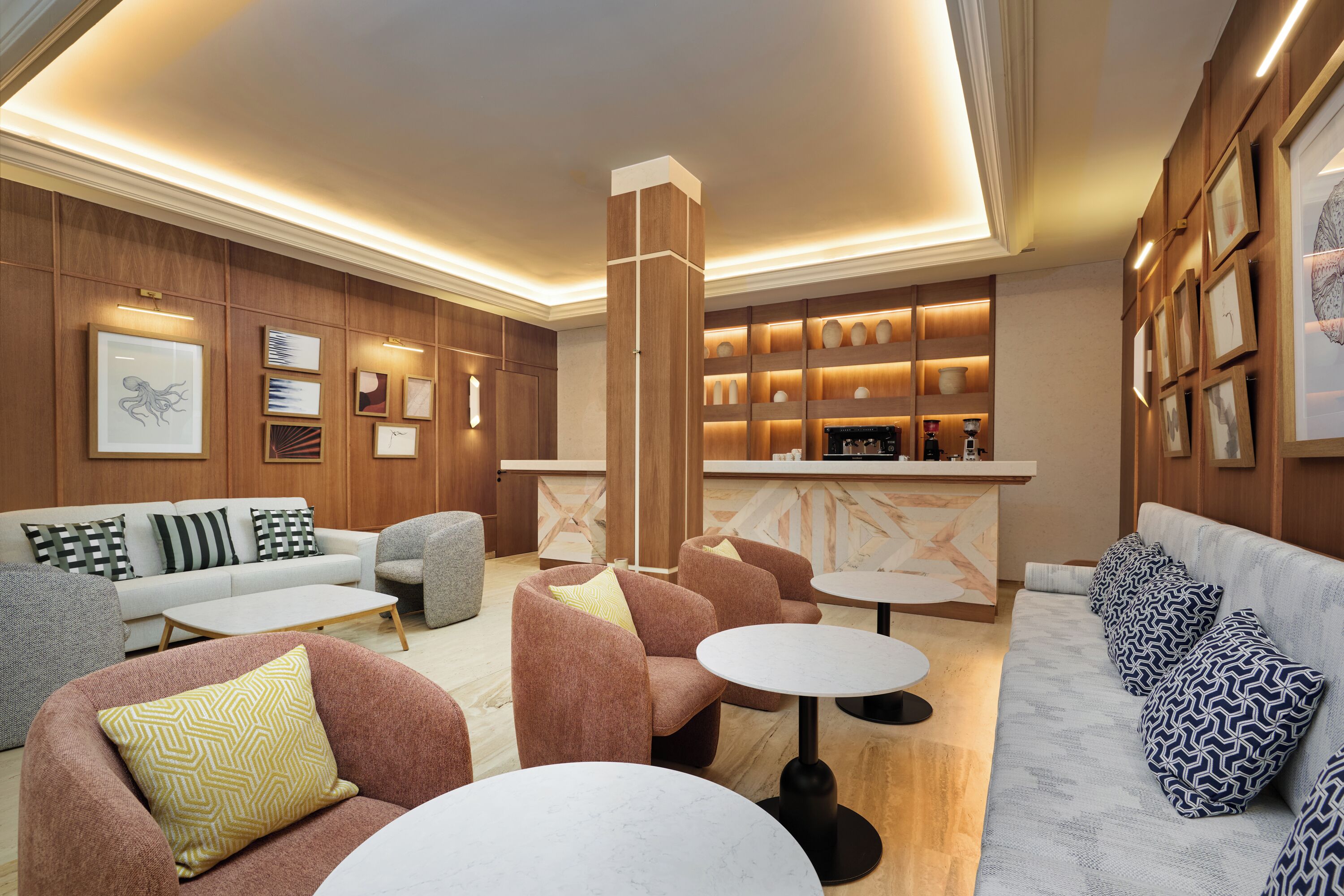 Un espacio lounge moderno con sofás, sillones y una barra de café.