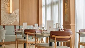 Ein Restaurantinnenraum mit Holzwandverkleidung, Ledersesseln und gedeckten Tischen.