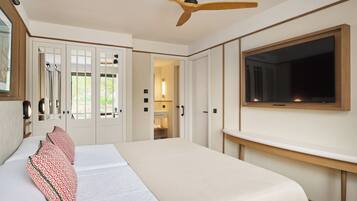 Ett hotellrum med en säng, en takfläkt, en TV och en dörr som leder till ett badrum.
