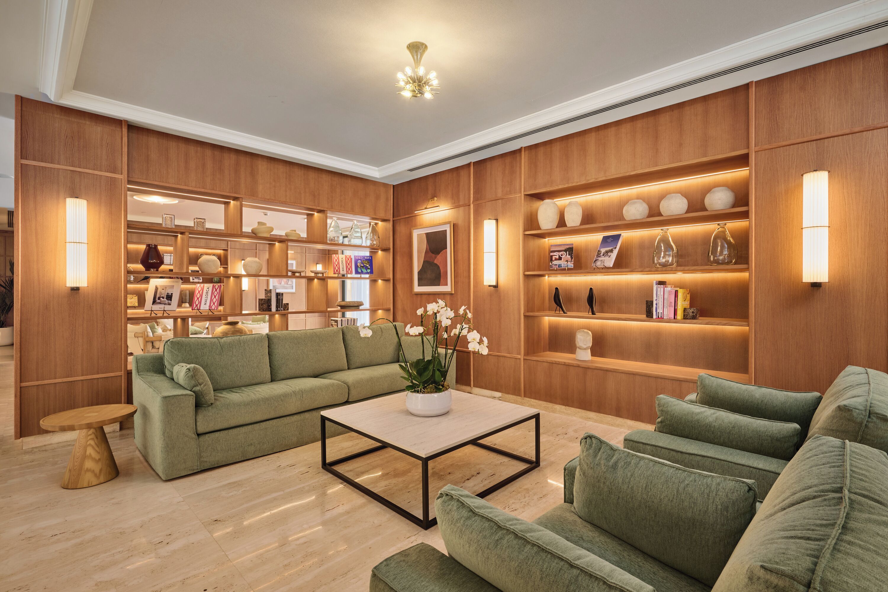 A modern living room with a green sofa, a coffee table, and wooden shelving with decorative items.