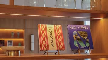 A shelf with two books titled 'Mallorca' and 'Mallorca A Taste of' and three clear glass bottles.