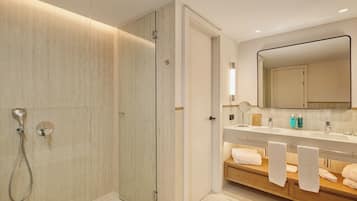 A modern bathroom with a glass-enclosed shower, a vanity with a mirror, and a wooden bench with towels.