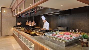 Un chef en una cocina moderna con una variedad de carnes exhibidas en la encimera.