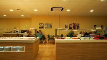 A buffet area with multiple serving stations, a microwave, and a seating area with chairs.