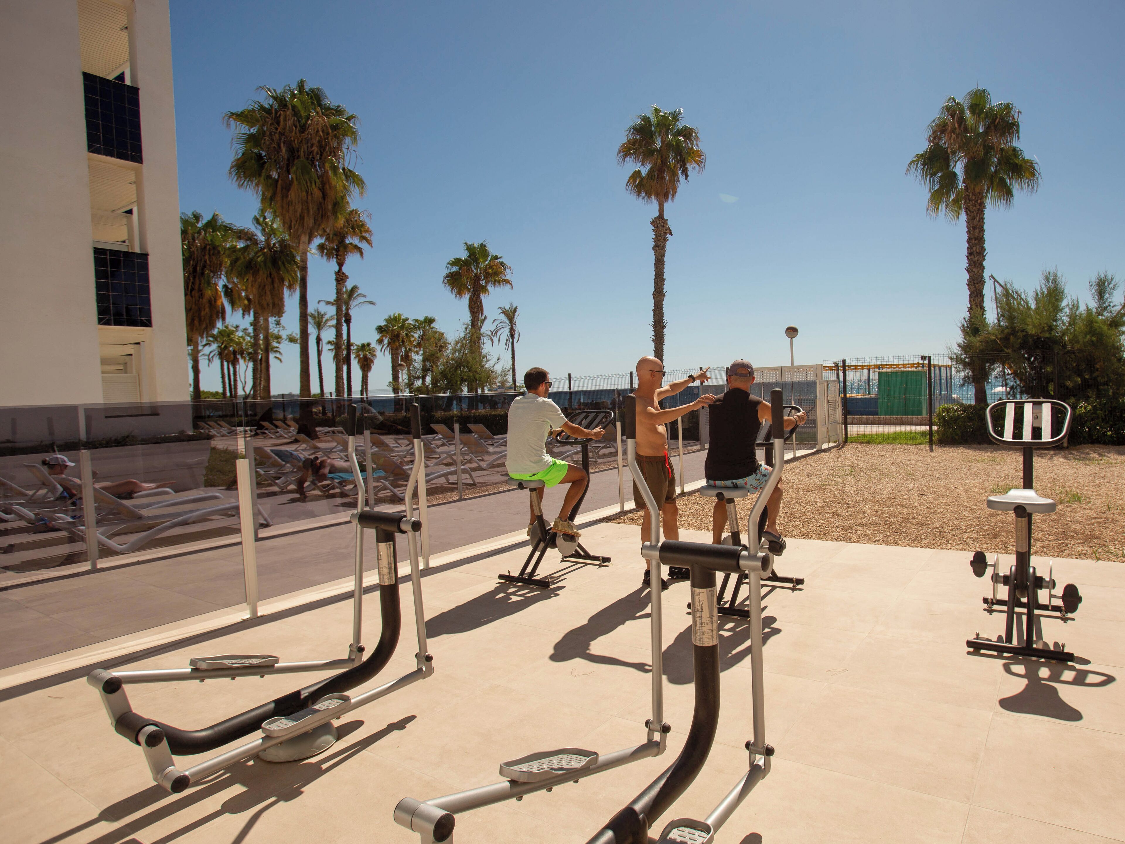 Outdoor exercise equipment, palm trees, and a building with balconies.
