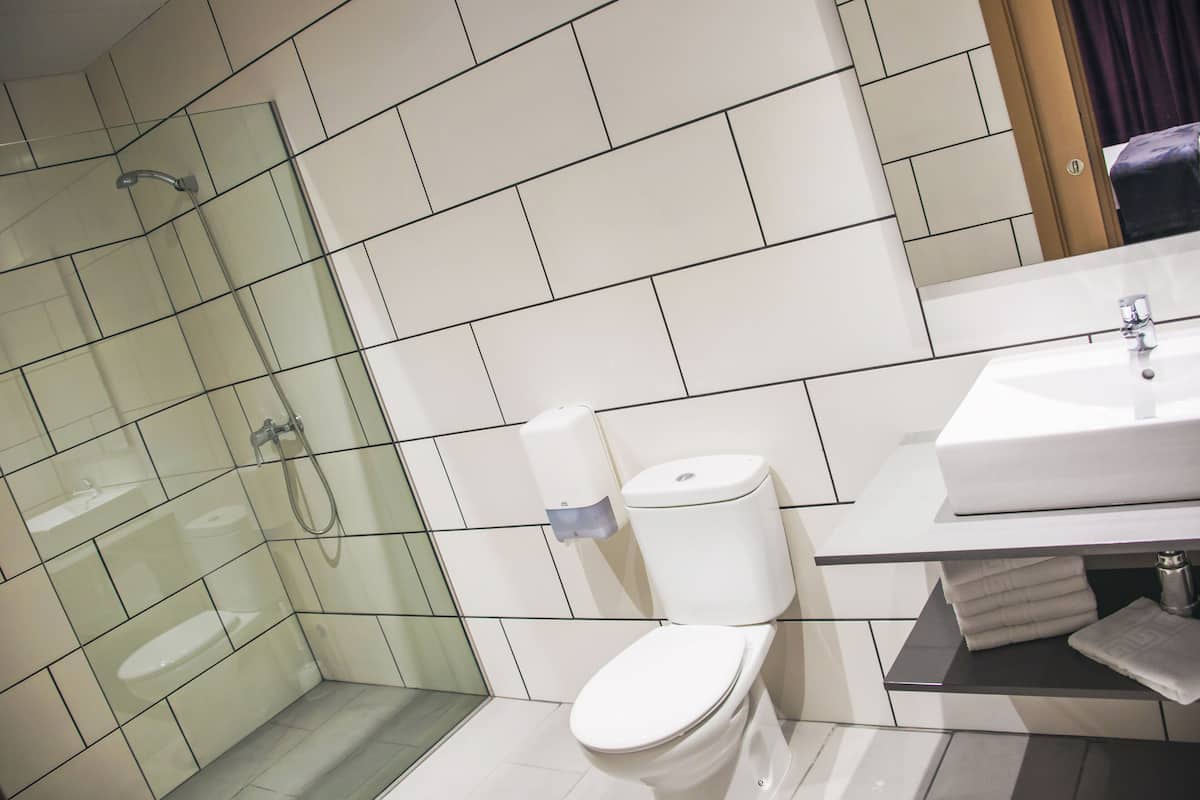 A modern bathroom with a glass shower enclosure, a white toilet, and a sink with a towel rack.