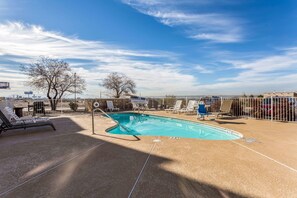 A swimming pool with lounge chairs and a fenced area, surrounded by buildings and trees. - Quality Inn & Suites El Paso I-10 (El Paso)