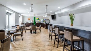 Een modern restaurant met houten vloeren, een bar en een flatscreen aan de muur.