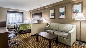 Een hotelkamer met een bed, een bank, een bureau, een stoel, een lamp en kunstwerken aan de muur.