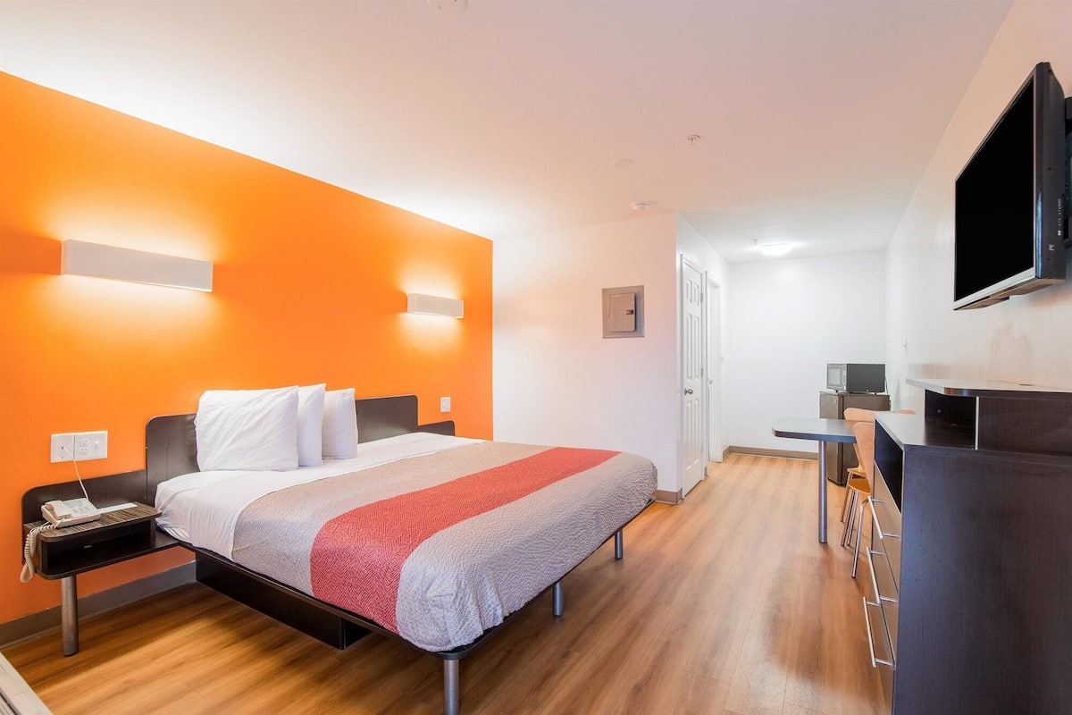 A hotel room with a bed, a desk, a TV, and a microwave.