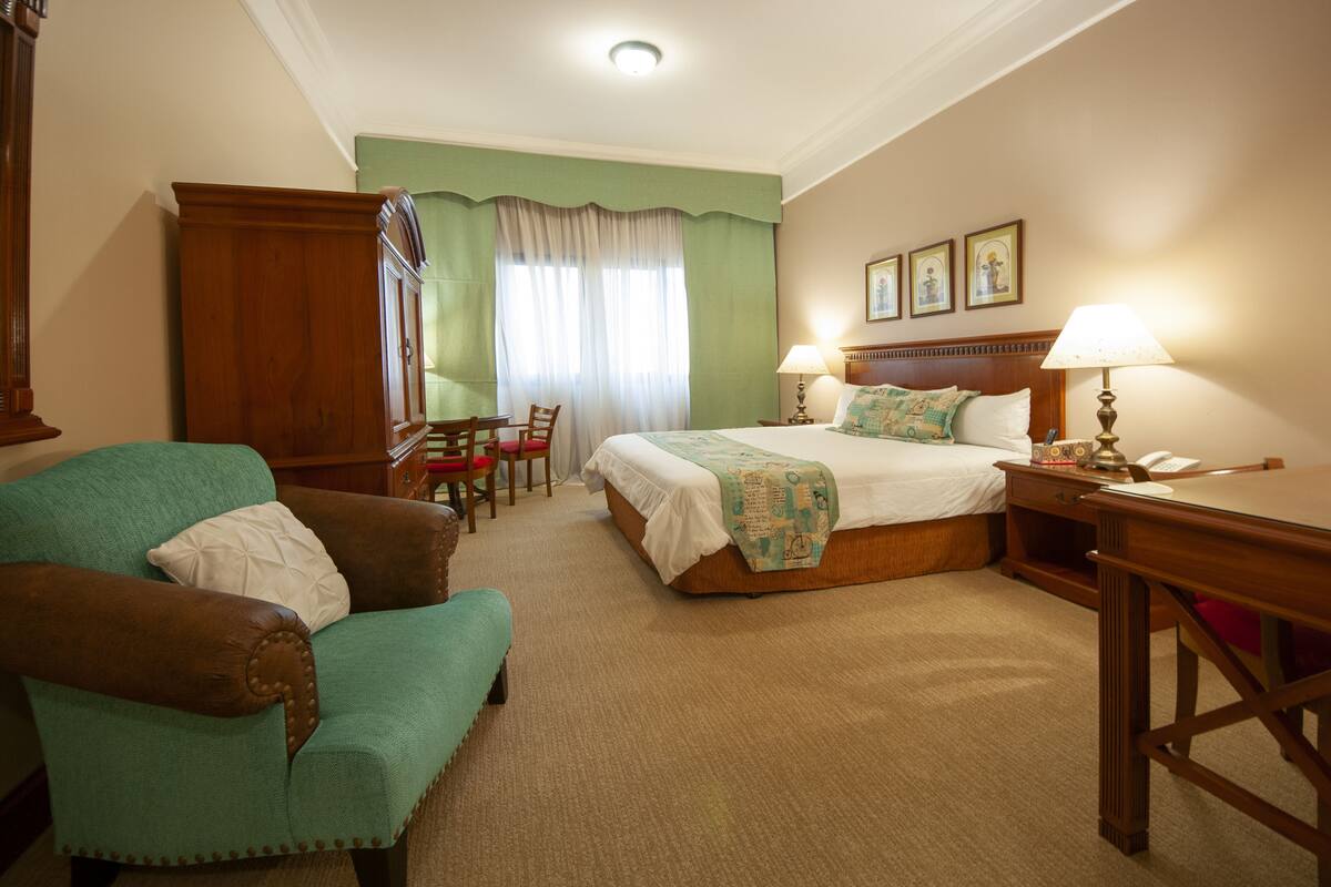 A hotel room with a bed, a desk, a chair, and a sofa.