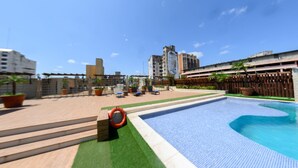 Una piscina con muelle de madera, escalones y plantas en macetas.