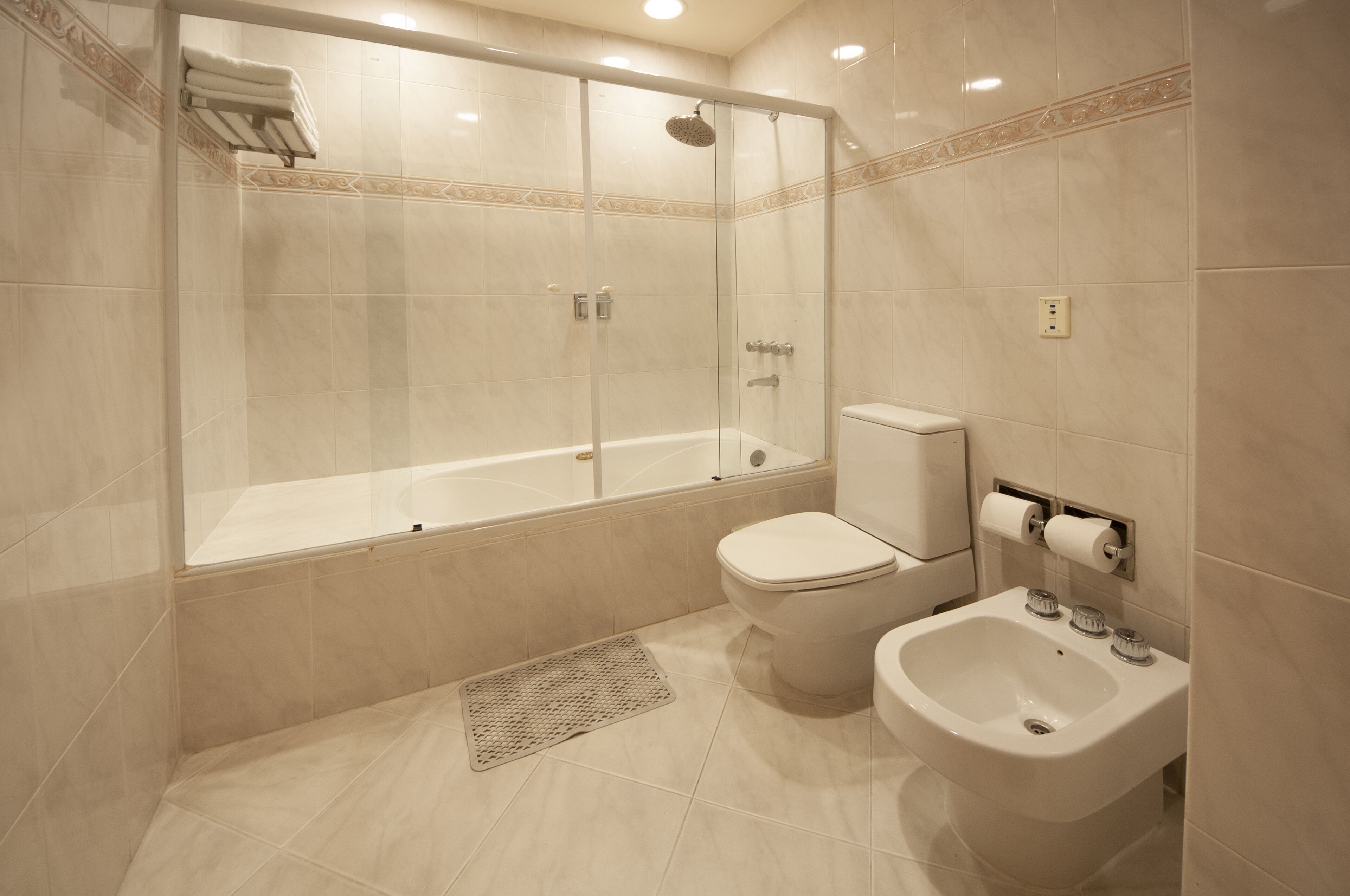 Une salle de bain moderne avec une douche à parois de verre, une baignoire, des toilettes et un bidet.