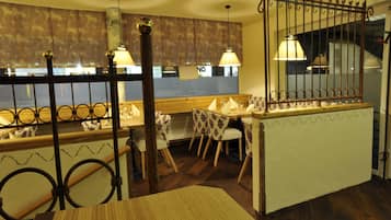 Interior de un restaurante con una mesa de madera que indica 'Renes Steakhouse', una zona de bar y sillas con estampado.