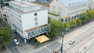 A hotel with a flat roof, large windows, and a covered outdoor seating area.