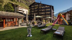 Un hotel con asientos al aire libre, sillones de descanso y un tobogán de colores.
