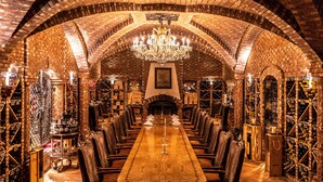 Una larga mesa de comedor con sillas, rodeada de paredes de ladrillo y un candelabro.