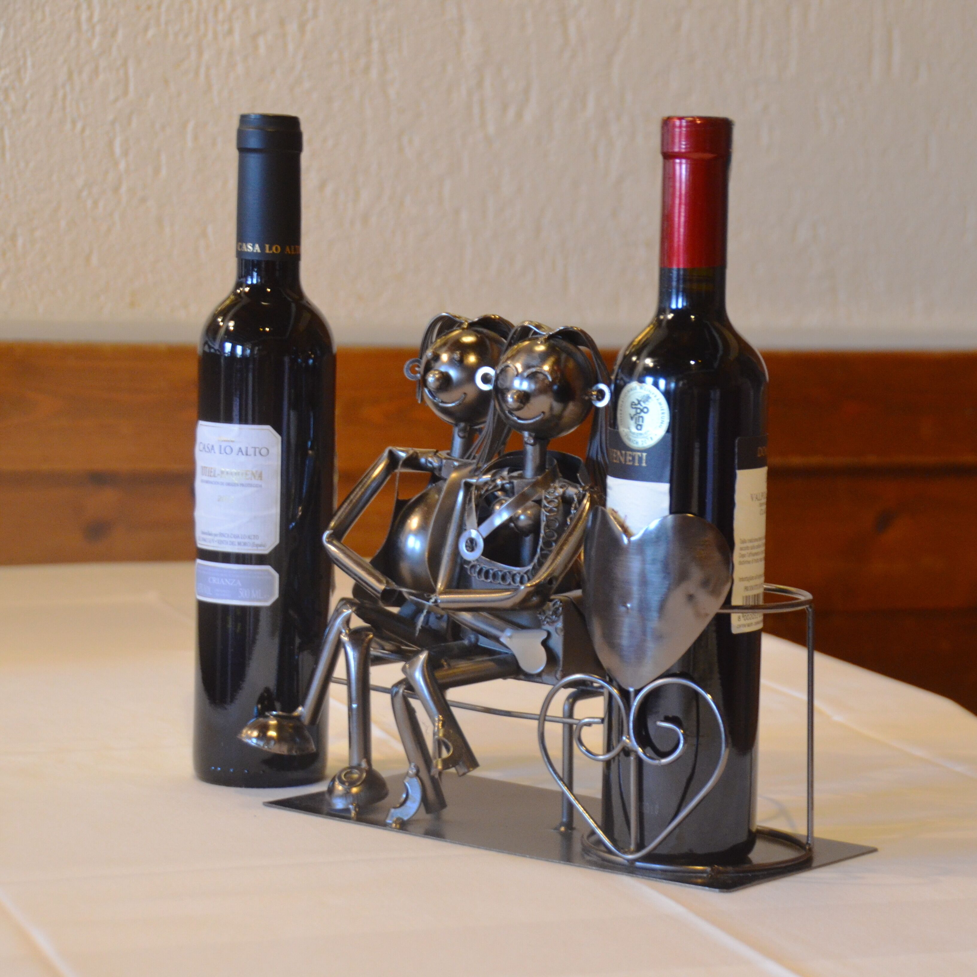 Une table avec deux bouteilles de vin et une sculpture en métal représentant un couple.