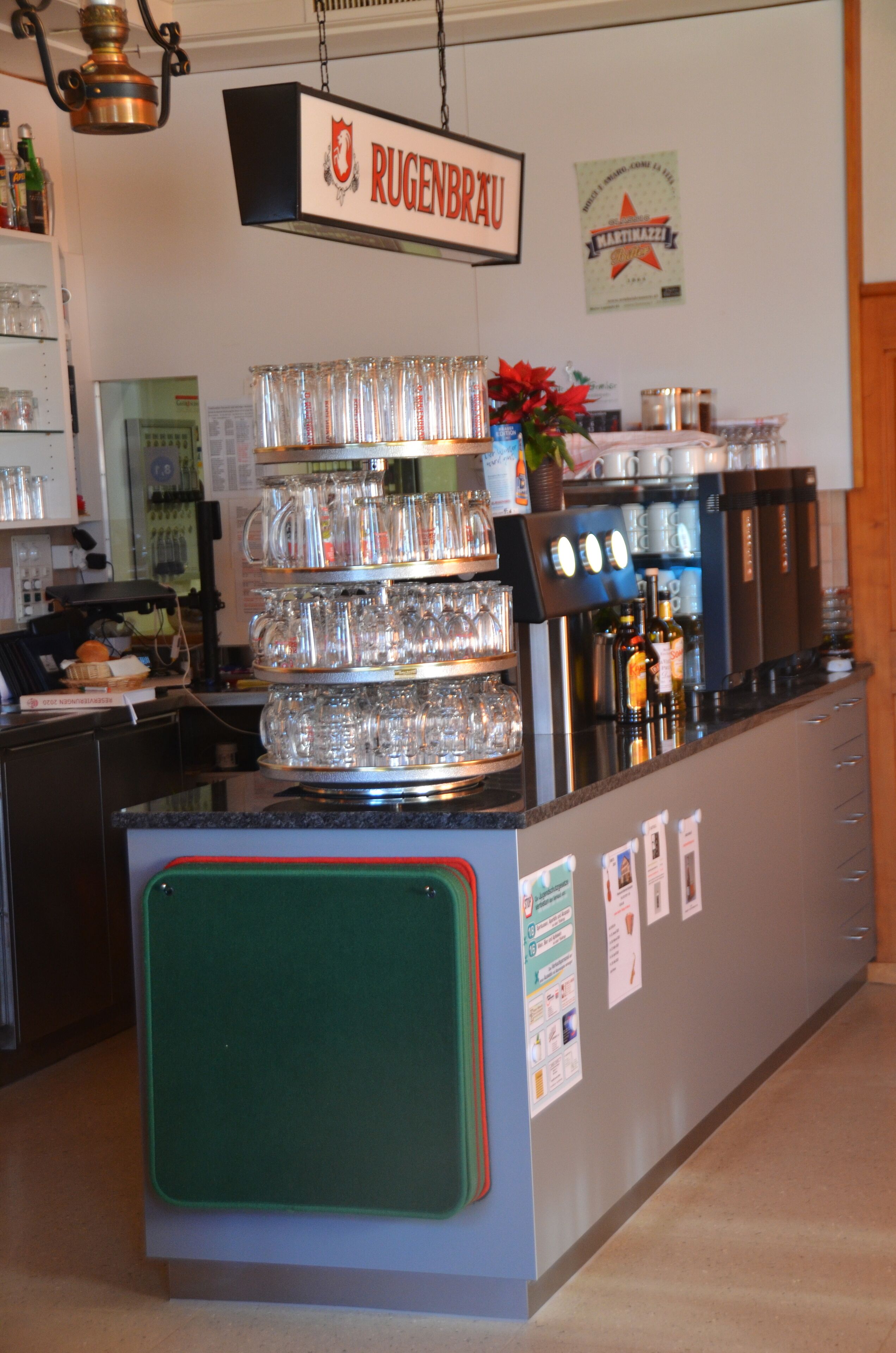 A bar area with a sign reading "RUGENBRAU" and a display of glassware.
