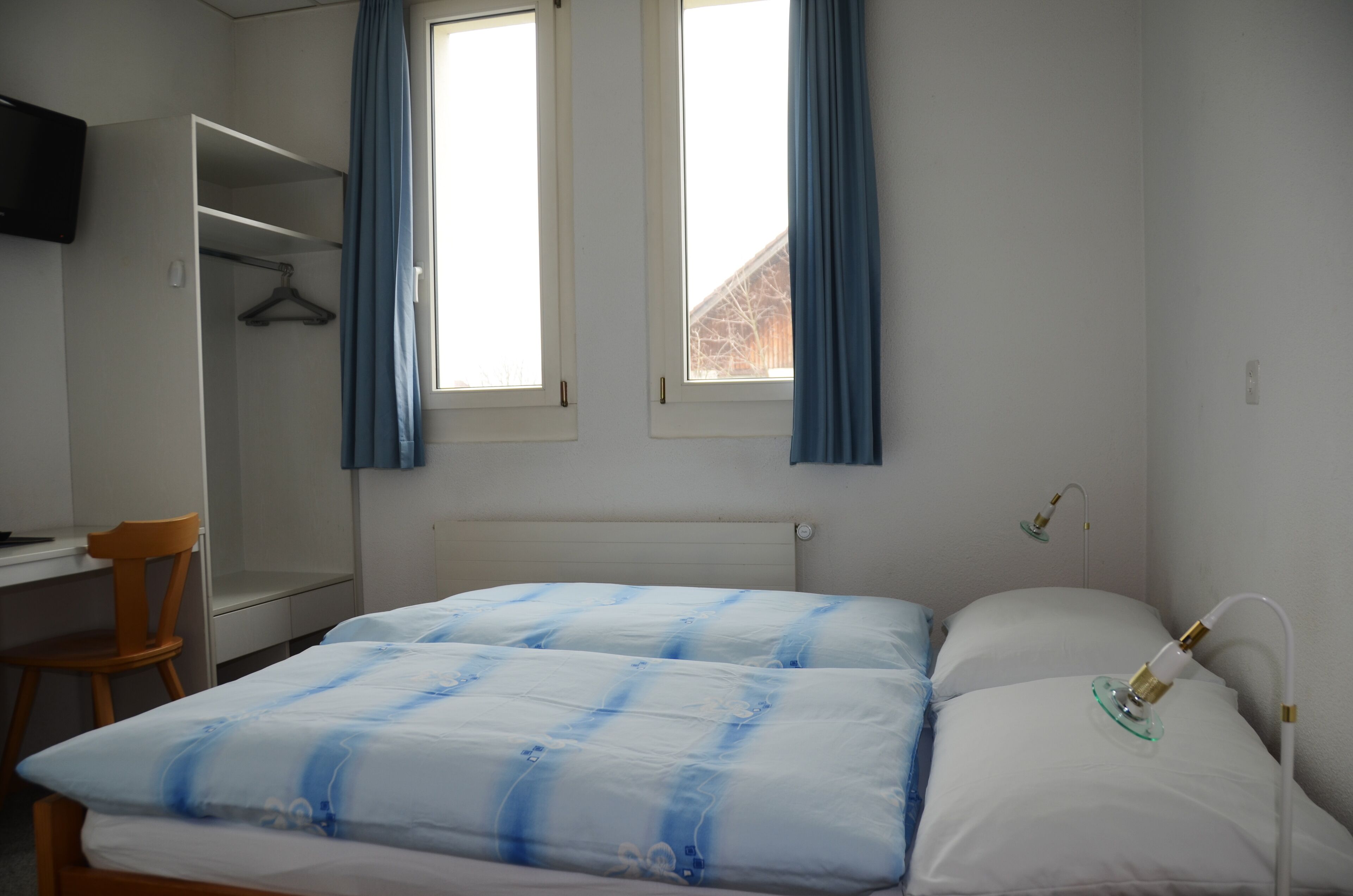 Un dormitorio con cama, escritorio, silla y armario.
