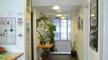 Un couloir avec un comptoir d’accueil, une plante en pot et une fenêtre donnant sur un paysage agréable.