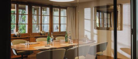A dining area with a long wooden table, six chairs, and a hanging light fixture.