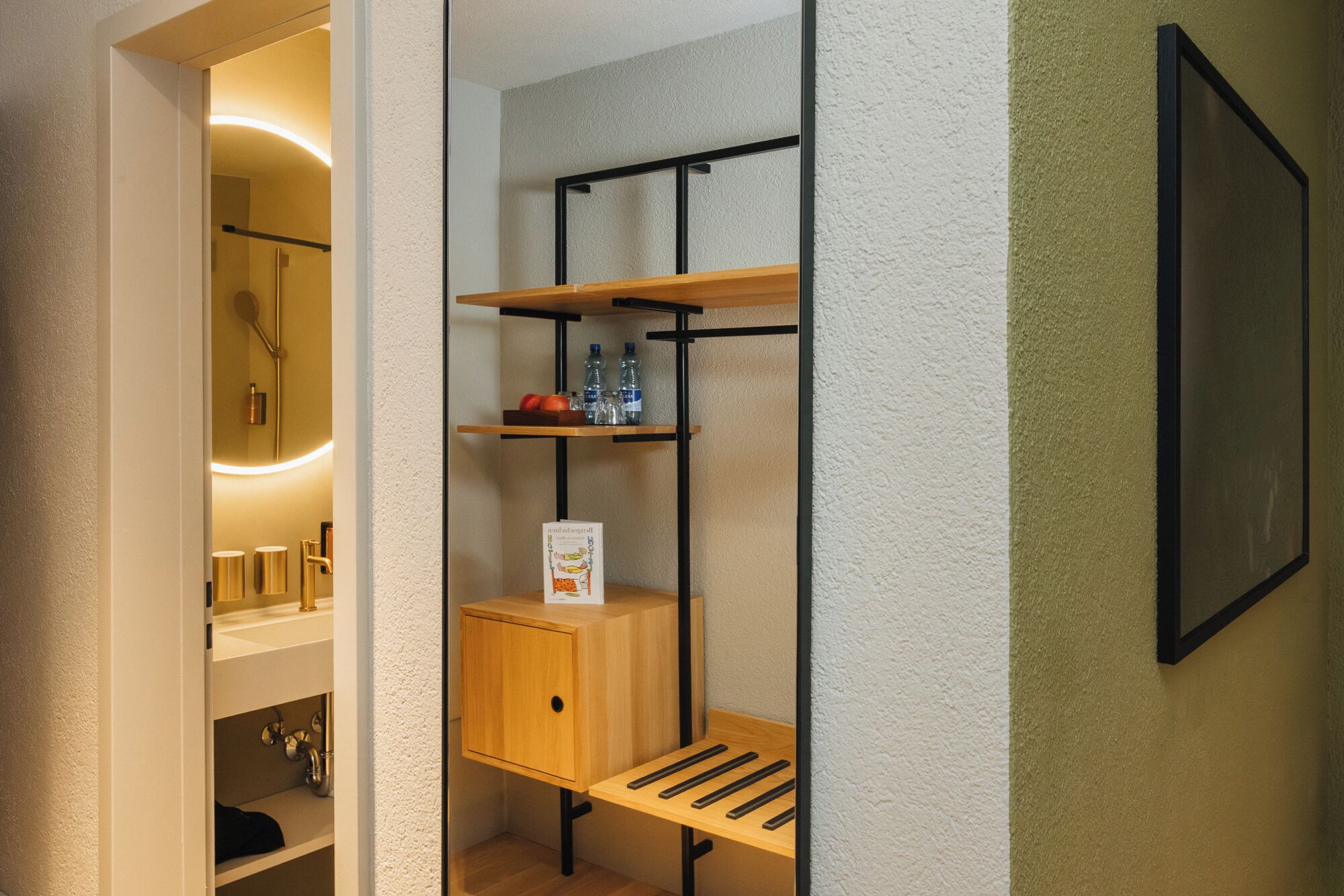A bathroom with a wooden shelf unit, a mirror, and a framed picture on the wall.