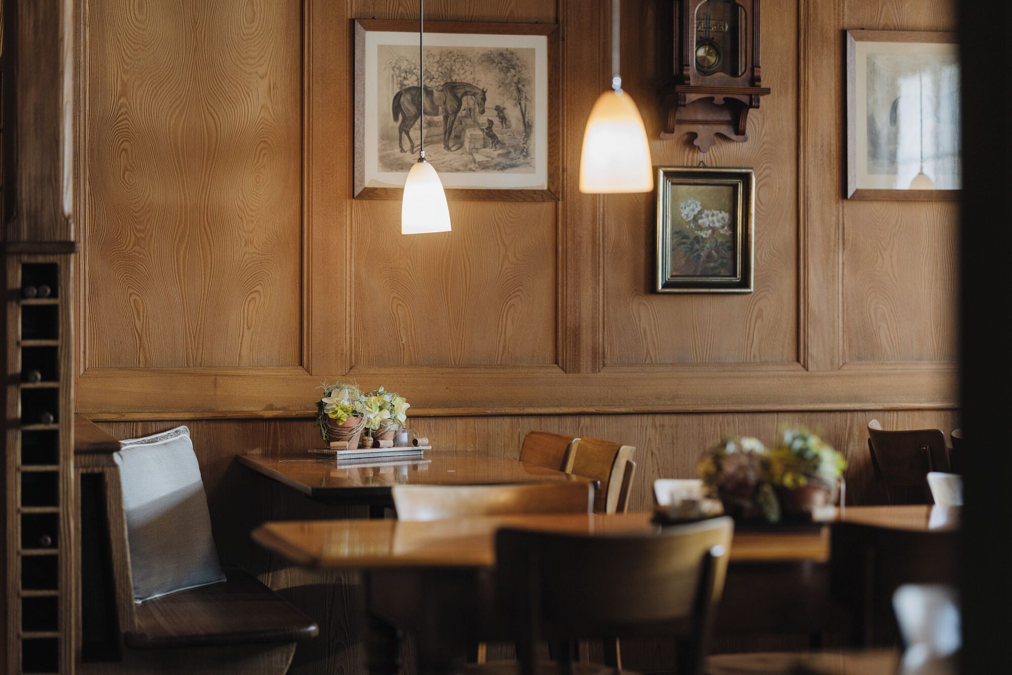 Una habitación con paneles de madera, una mesa de comedor, sillas y lámparas colgantes.